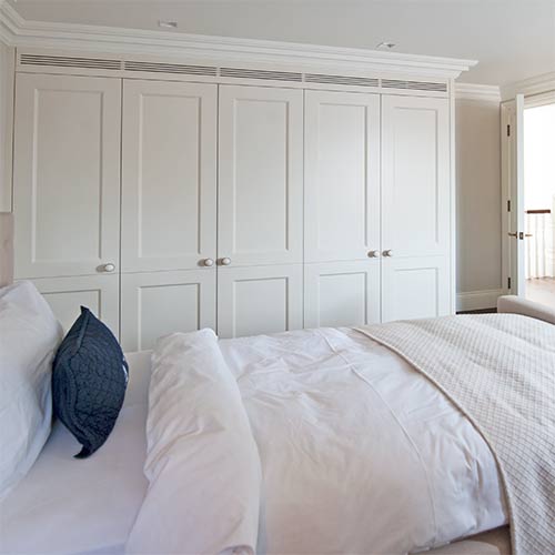 A clean white bed and wardrobe