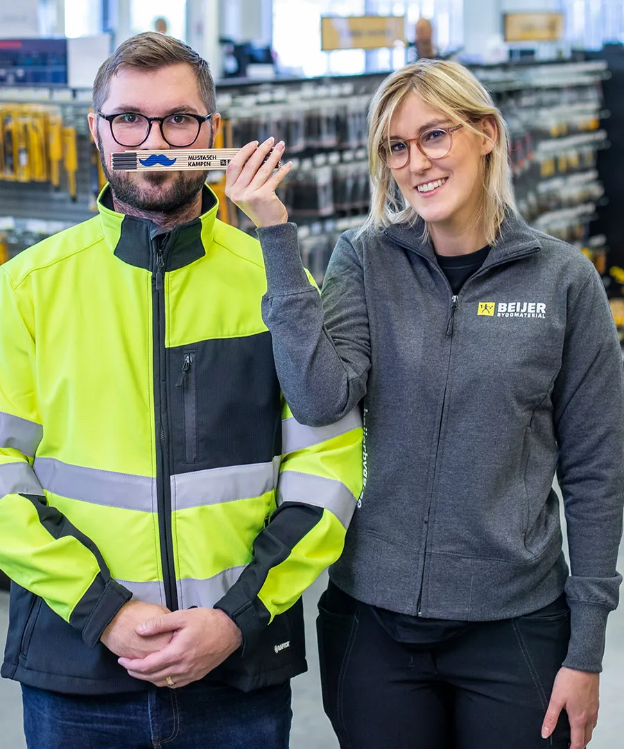 Två medarbetare från Beijer med en mustaschprydd meterstock.