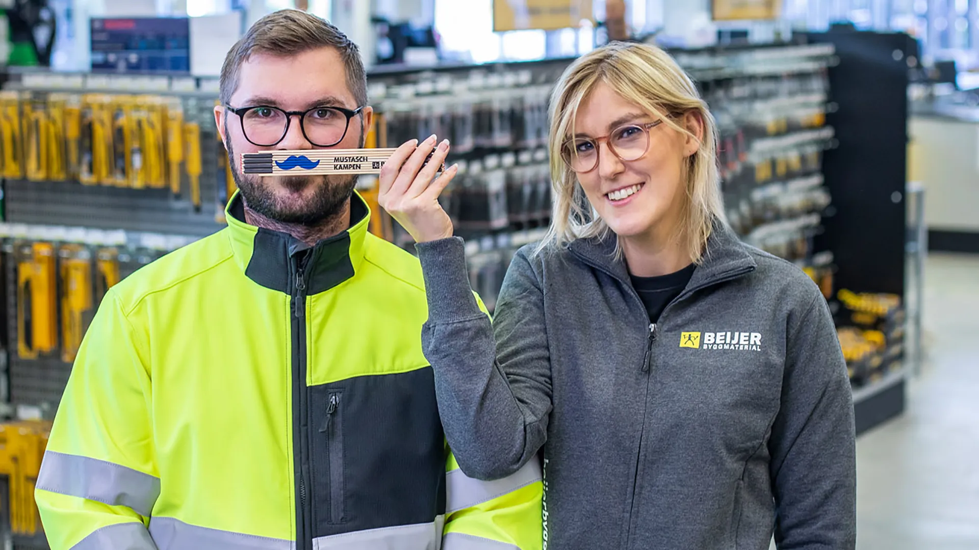 Två medarbetare från Beijer med en mustaschprydd meterstock.