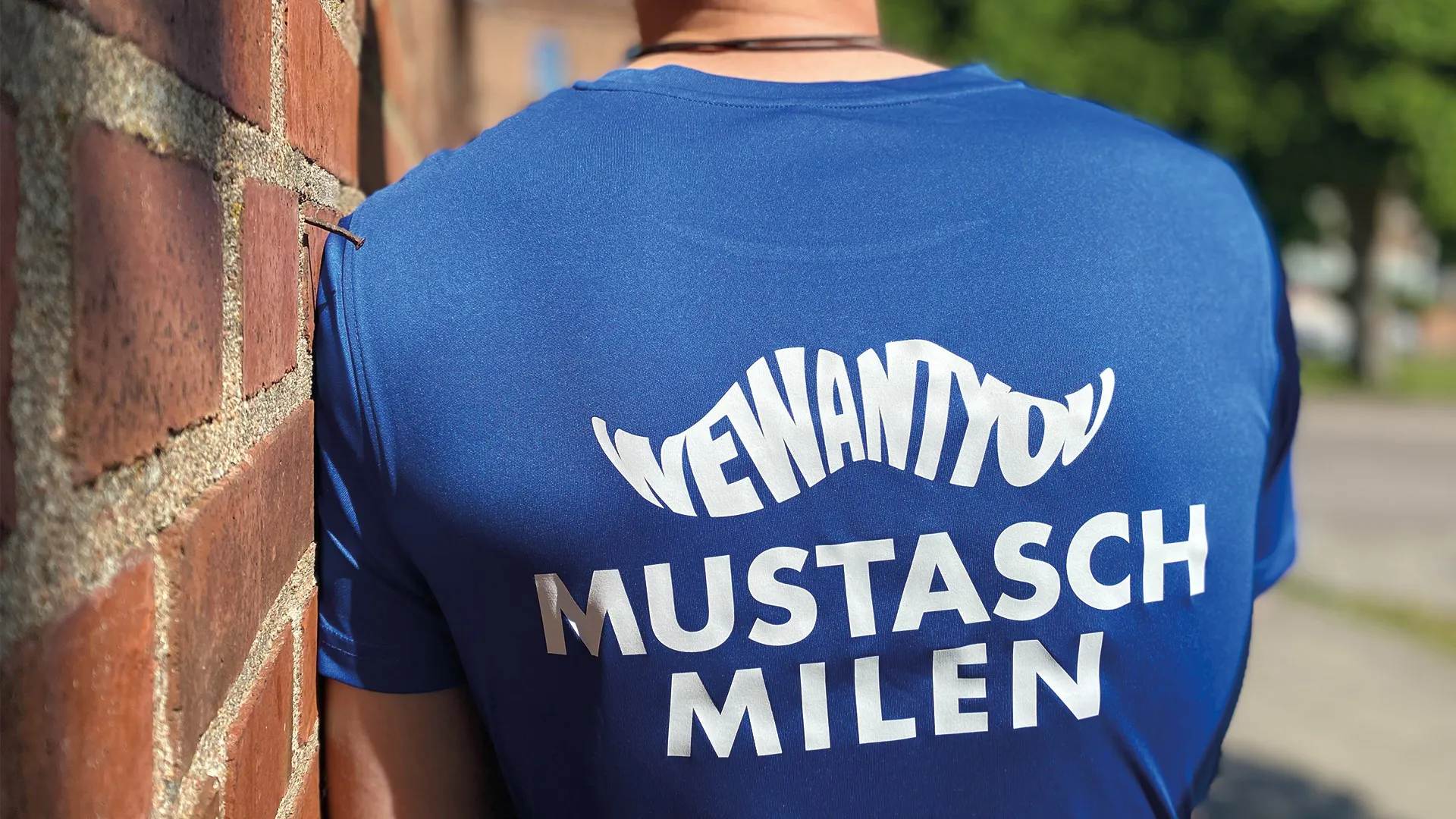 Man iklädd en blå Mustaschmilen-tröja