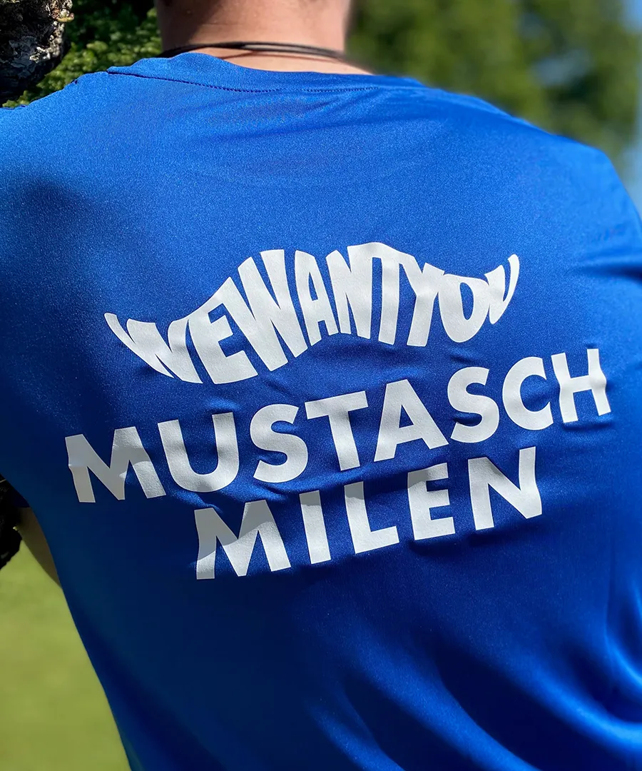 Man iklädd en blå Mustaschmilen-tröja