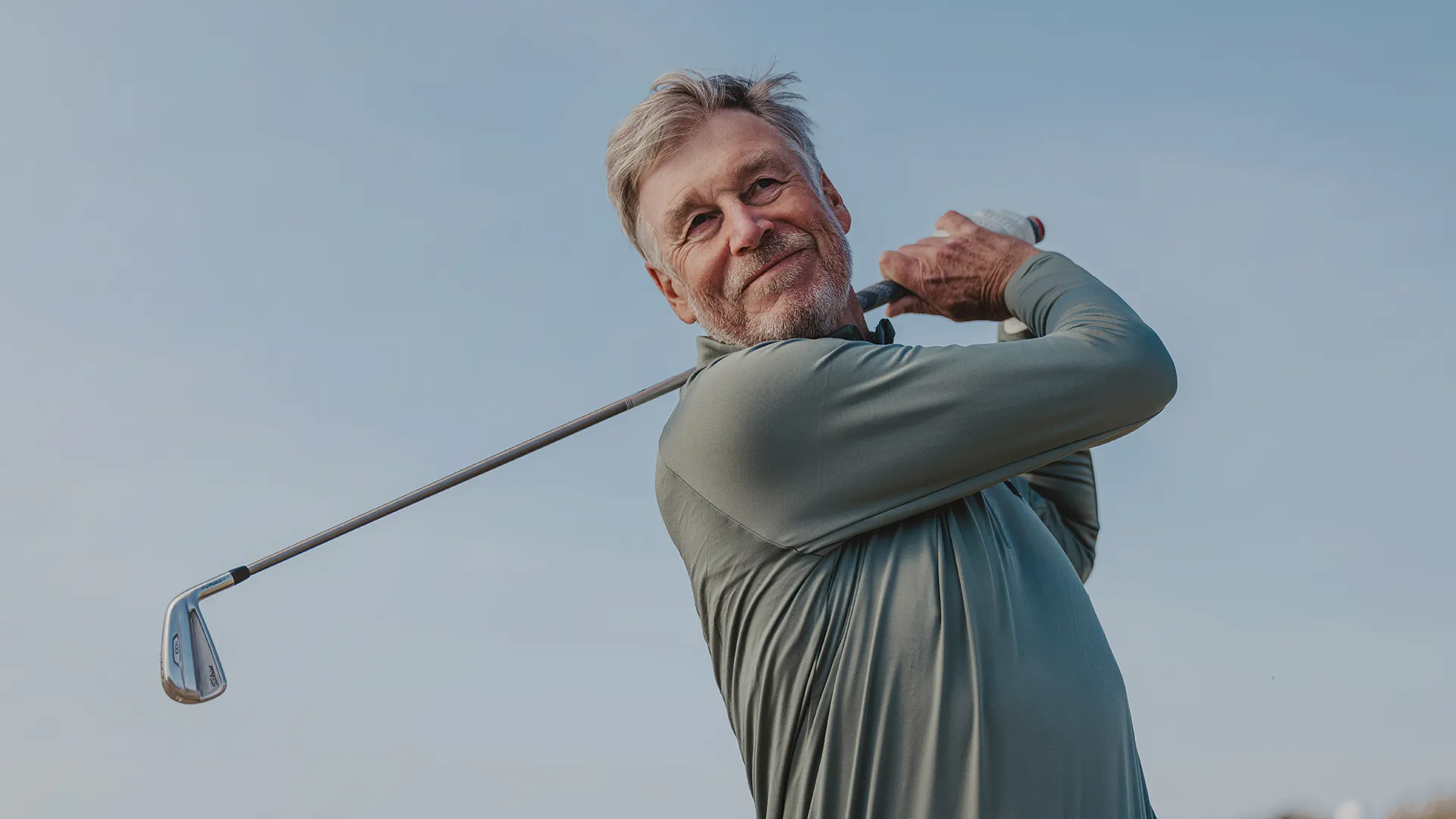 Man som svingar en golfklubba.