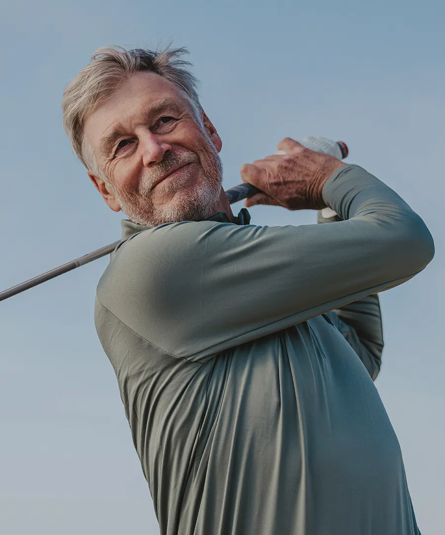 Man som svingar en golfklubba.