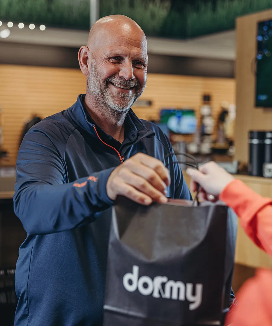 Glad äldre man tar emot en påse i butik