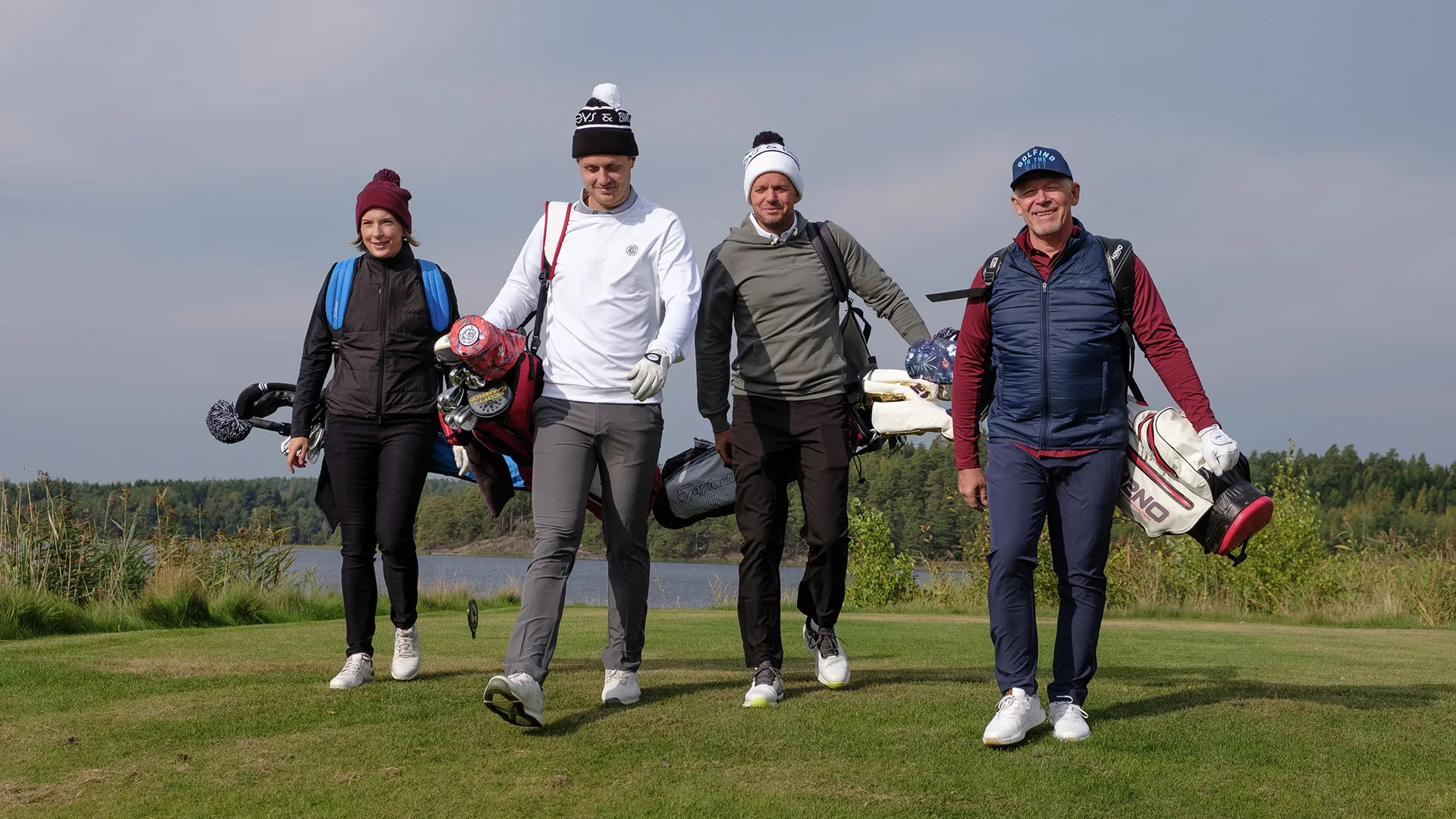Fyra glada personer med golfutrustning på golfbanan