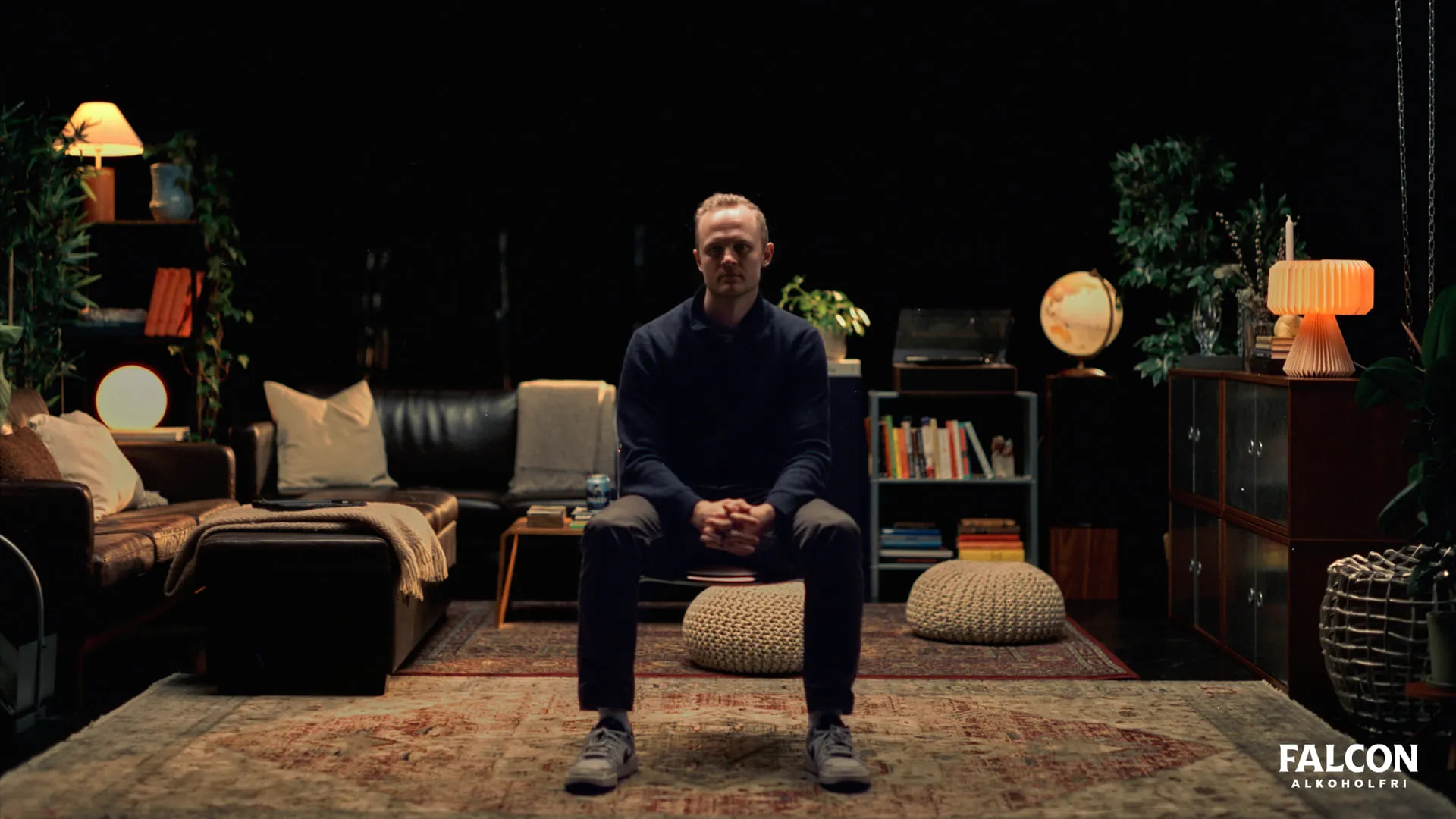 Ung allvarlig man sitter på en stol i ett vardagsrum
