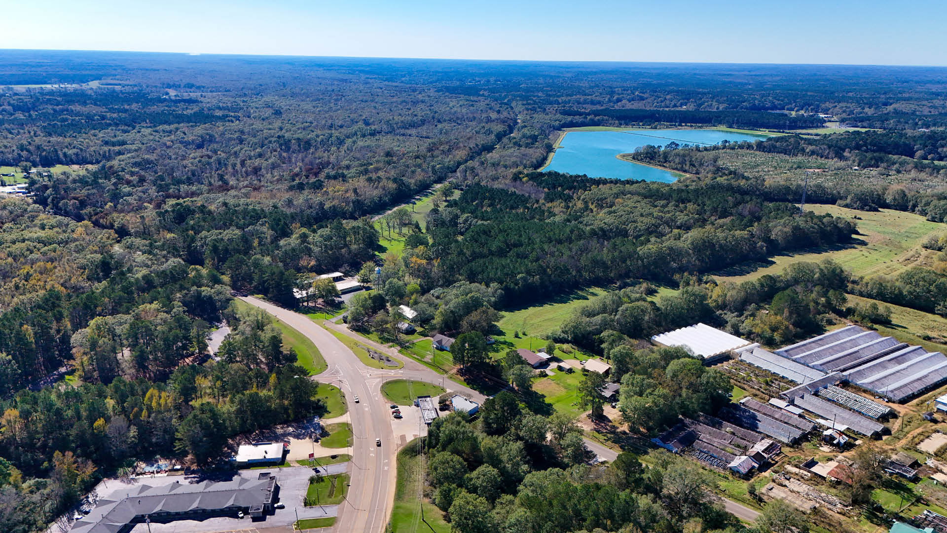 Aerial view of forested land for sale in Choctaw County, Mississippi, featuring a long road through green acreage starting at $15,400.