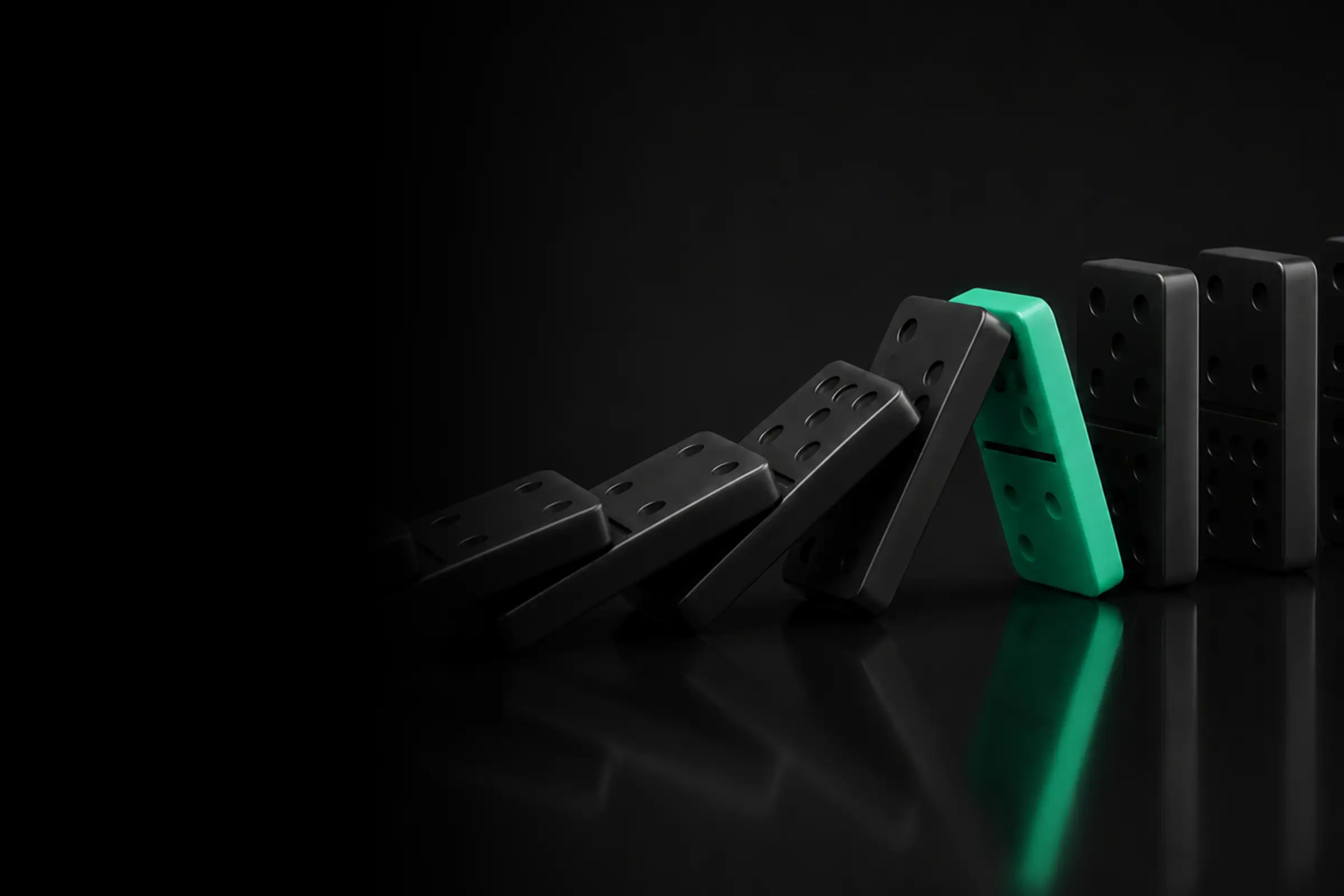 A green domino blocking a chain reaction of falling black dominoes on a reflective black surface.