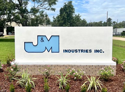 J&M Industries concrete sign in the garden in front of the building