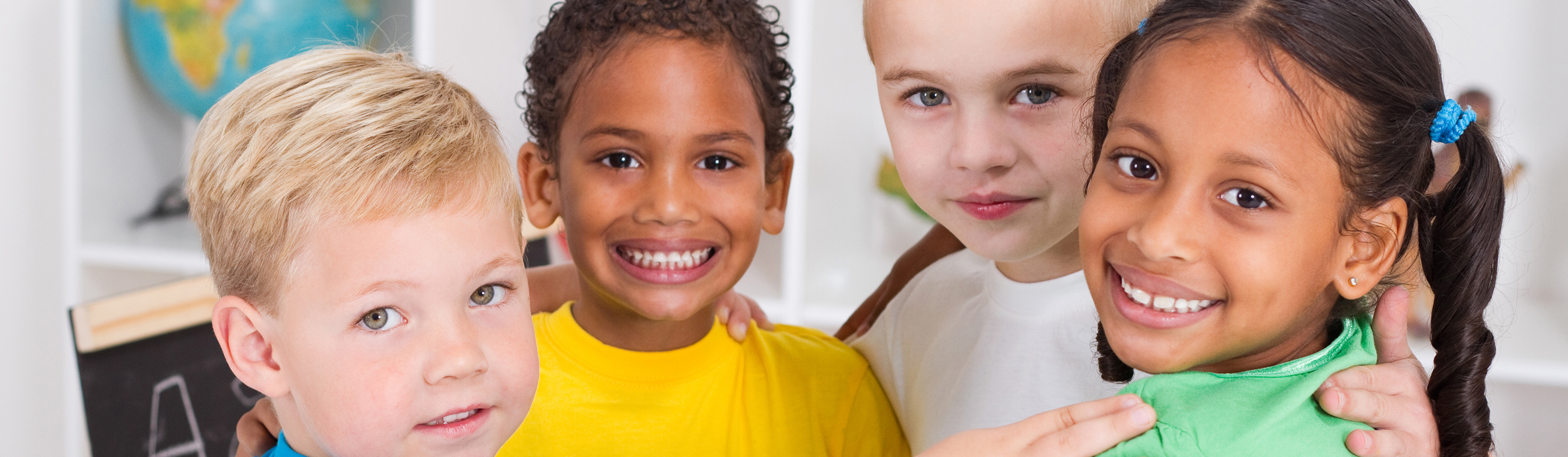 Four smiling preschool children in a classroom.