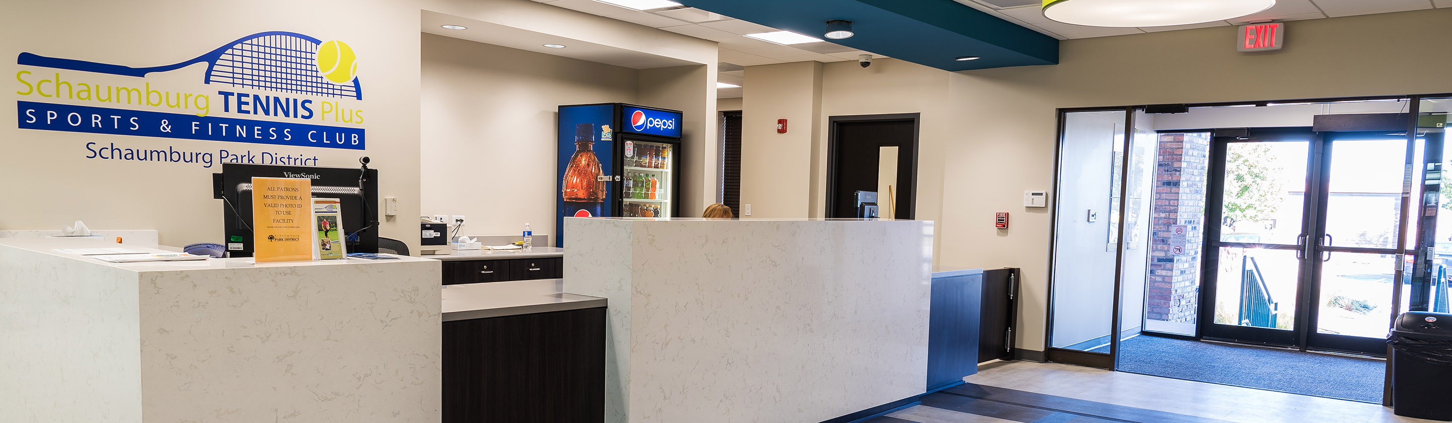 Schaumburg Tennis Plus lobby and front desk with the "Schaumburg Tennis Sports & Fitness Club" logo.