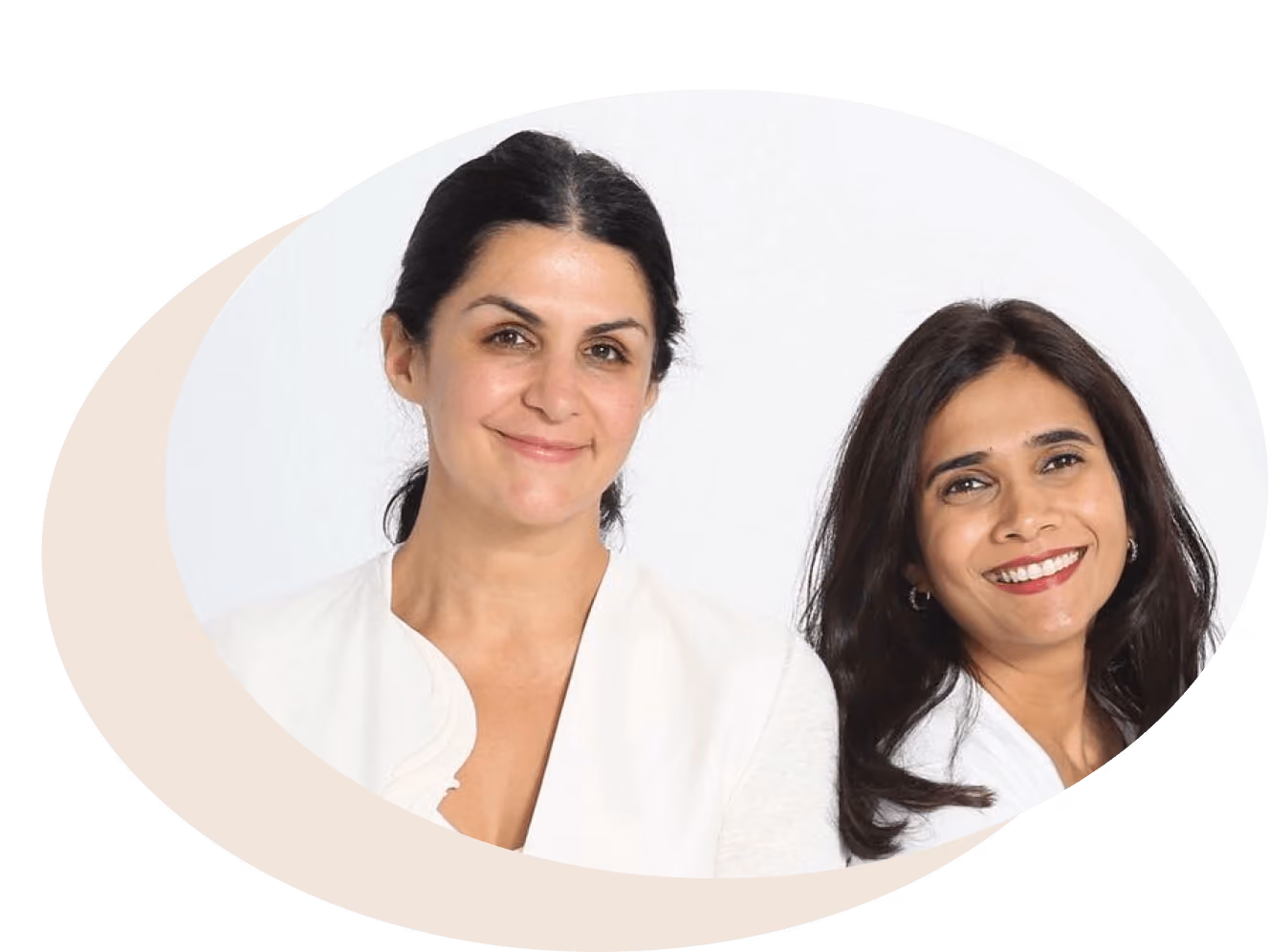 Two women smiling, one with dark tied-back hair wearing a white top, and the other with dark loose hair wearing a white shirt.