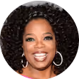 Smiling woman with curly hair wearing large hoop earrings and mauve lipstick.