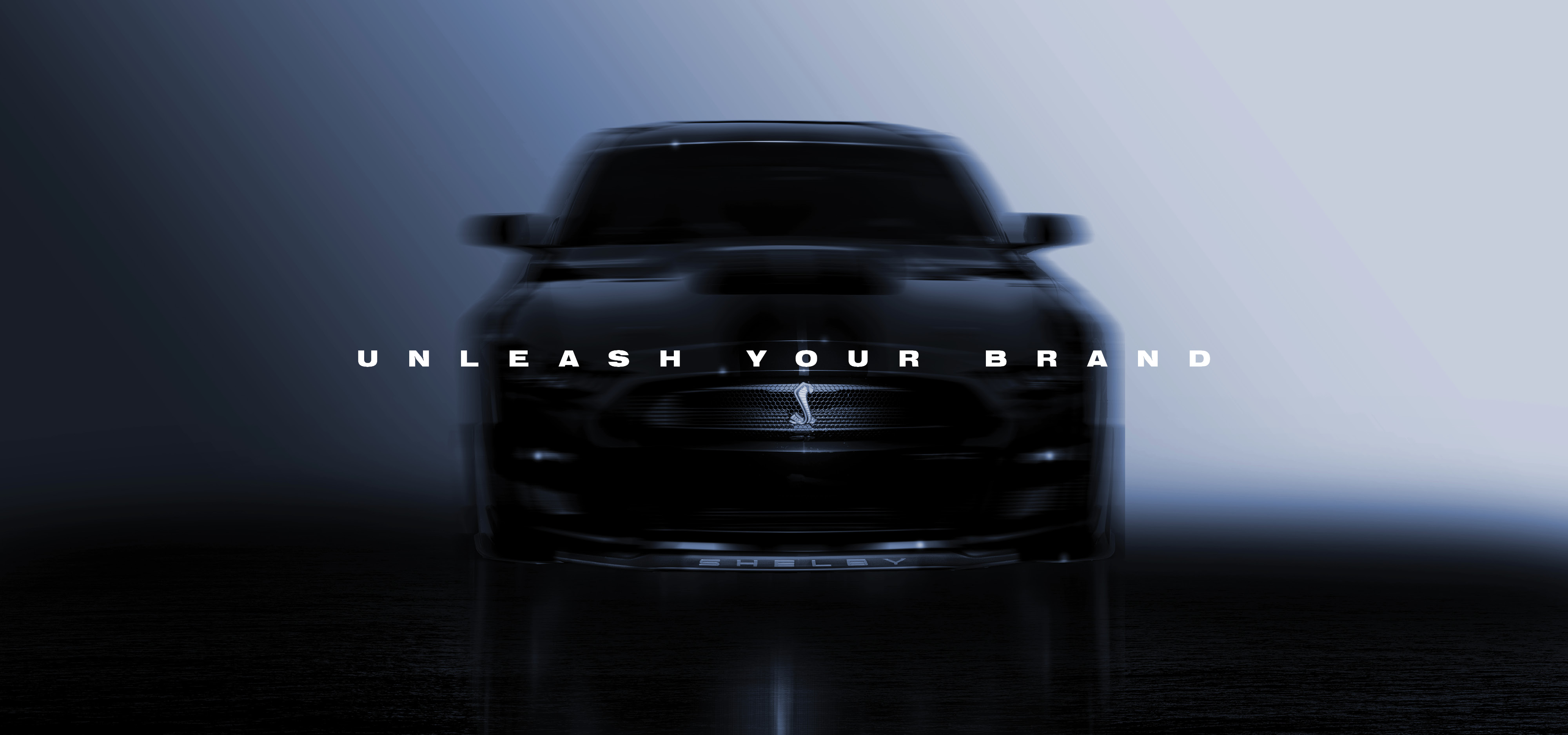 Front view of a black Shelby car with a blurred effect and the text 'UNLEASH YOUR BRAND' across the middle.