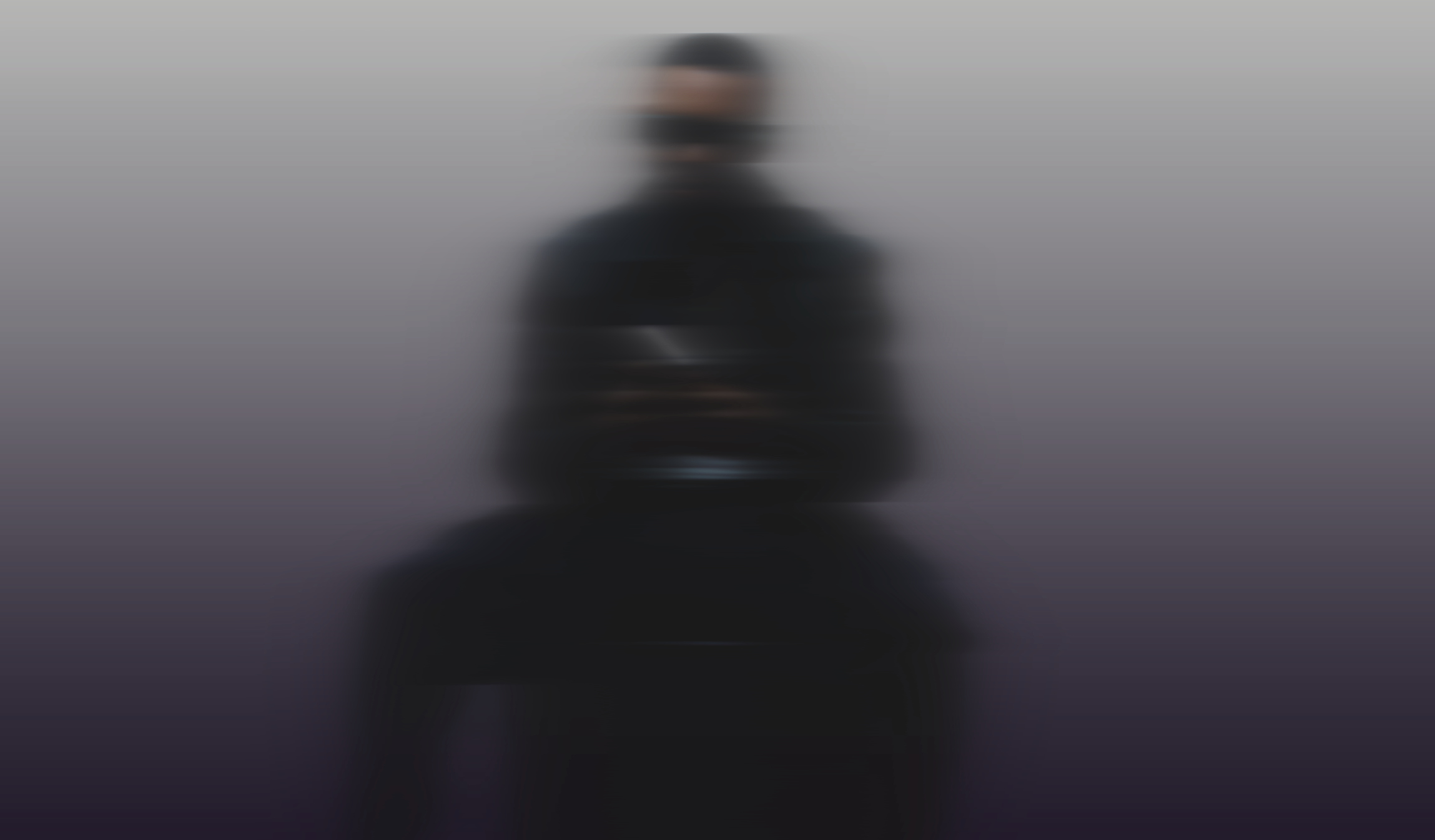 Blurred image of a person dressed in black against a gradient background.