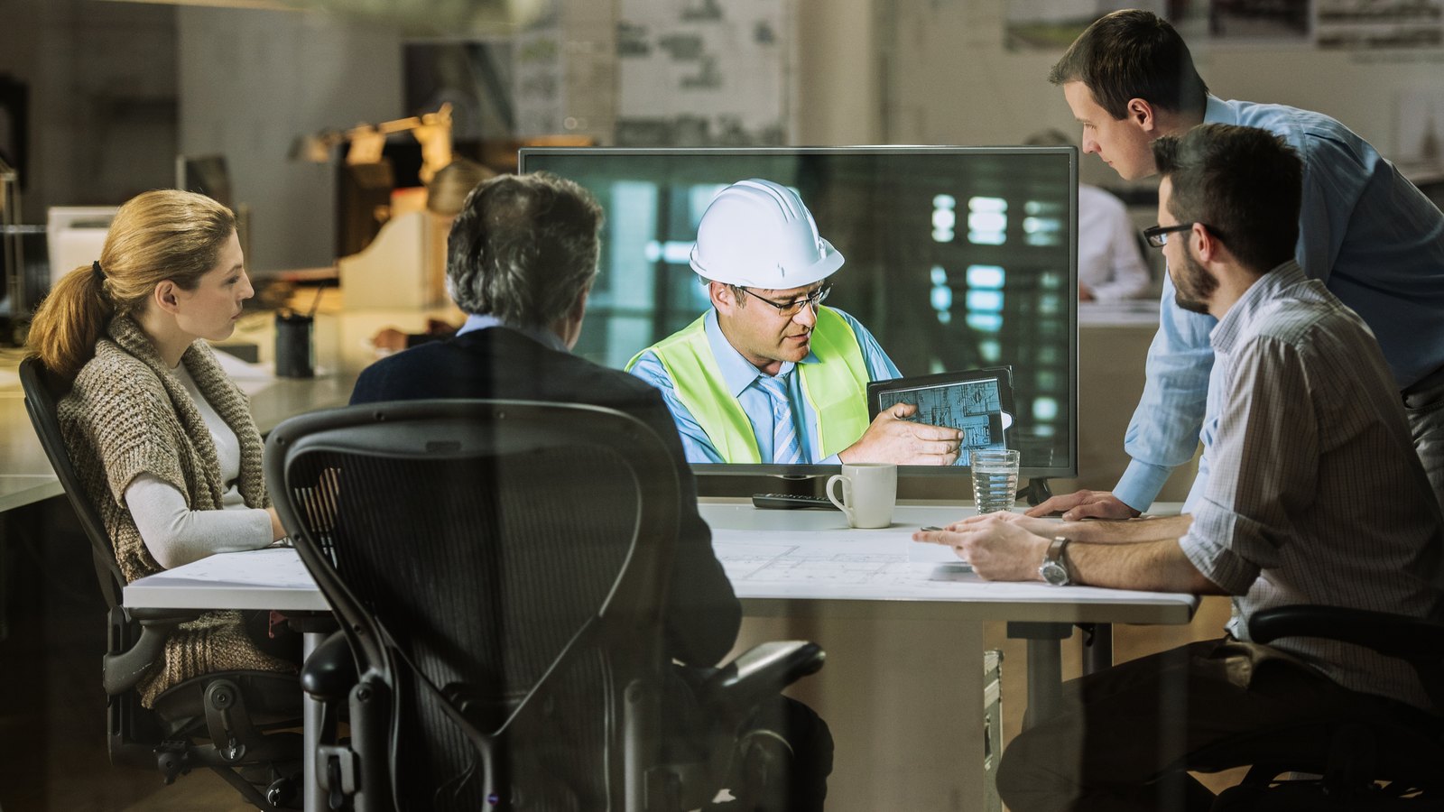Construction team coordinating technology and electrical work from project plans