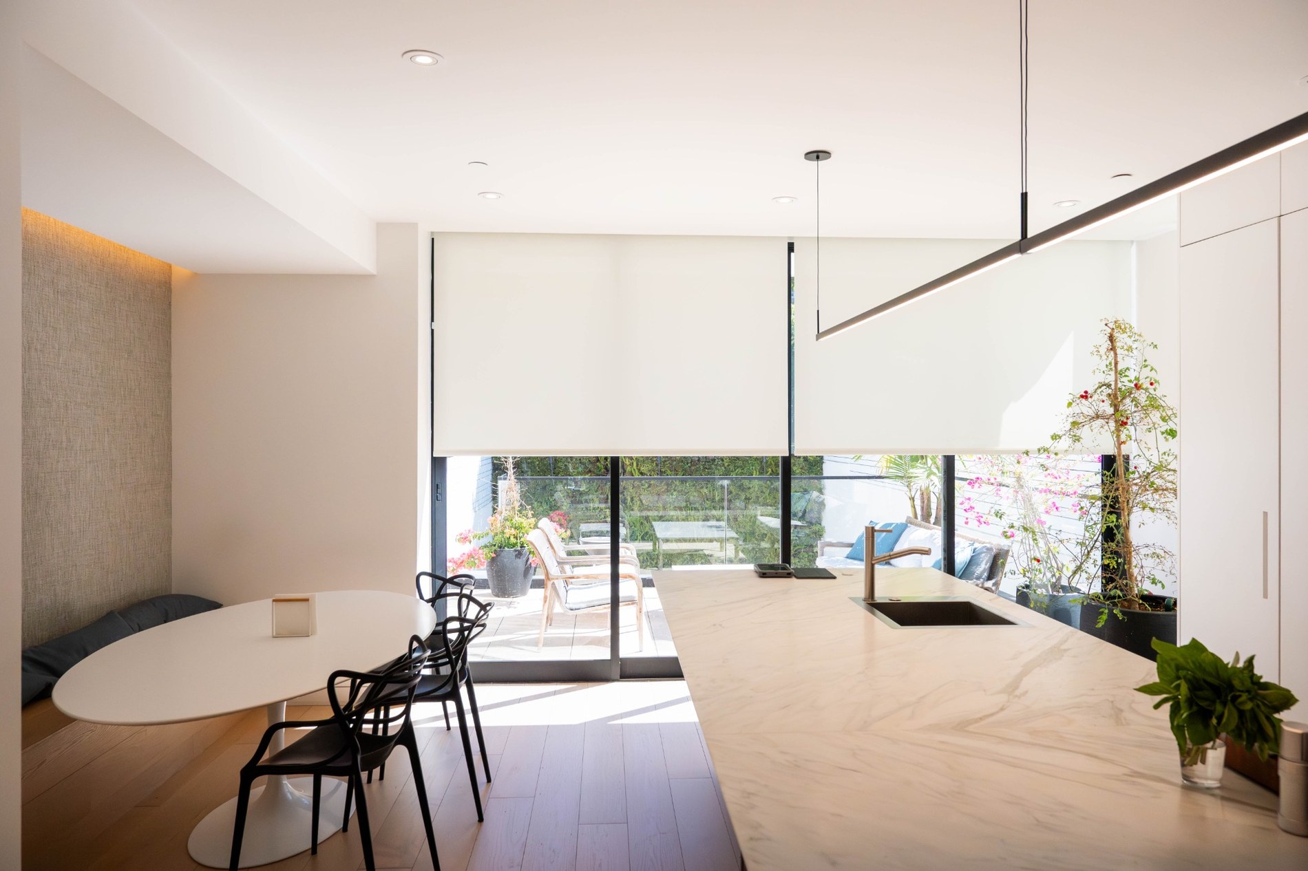 Modern luxury kitchen with motorized roller shades and linear pendant lighting