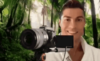 a man is taking a selfie with a camera in front of a green background .