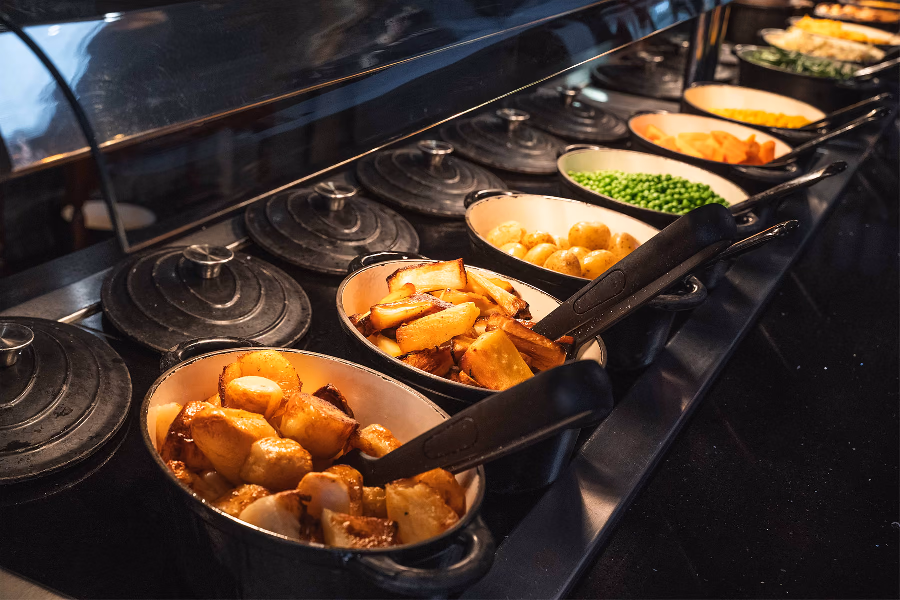 Sunday carvery with roasted meats and Yorkshire puddings arranged on a white serving board in a buffet display.