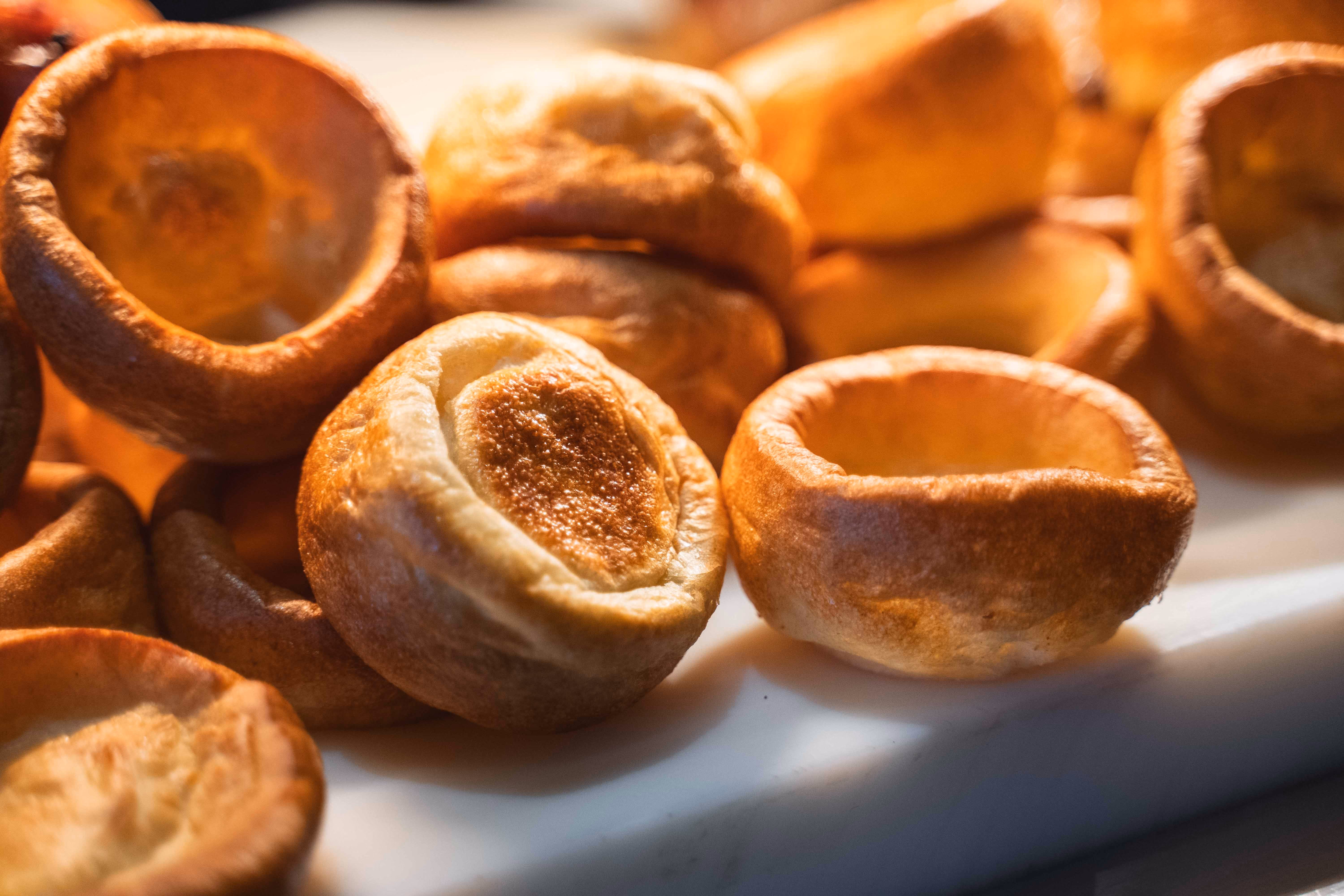 Sunday carvery with roasted meats and Yorkshire puddings arranged on a white serving board in a buffet display.