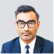 A man in a suit and tie wearing glasses.