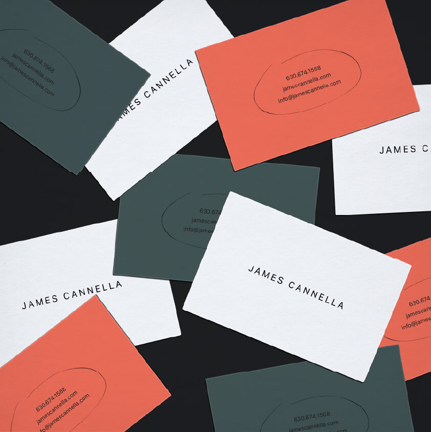 Scattered business cards with three different designs: white cards displaying 'JAMES CANNELLA', dark green cards and red cards featuring contact details including phone number and email.