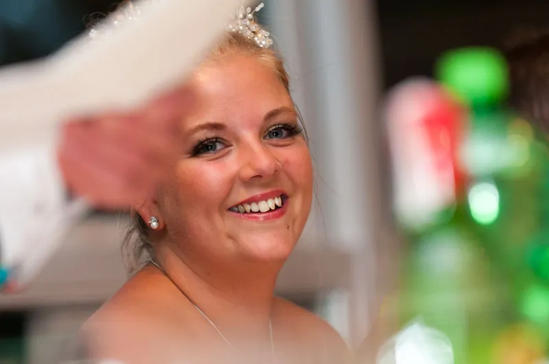 Smiling bride with pearl hair accessory and diamond earrings looking at the camera.