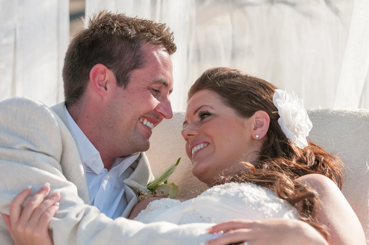Smiling bride and groom embracing and looking lovingly into each other's eyes.