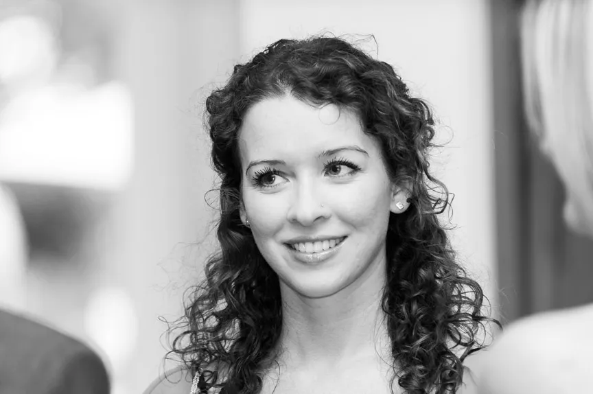 Black and white portrait of a smiling woman with curly hair looking slightly to the side.