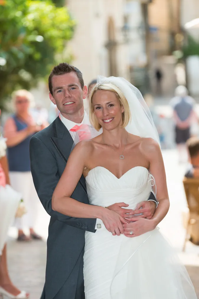 Bride and groom smiling and embracing outdoors on their wedding day.