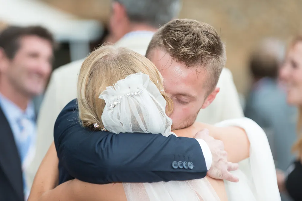 Groom hugging bride wearing a hair veil with decorative pins during a wedding celebration.