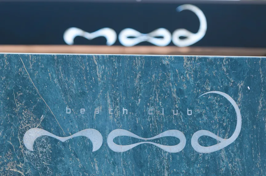 Close-up of a blue-green textured surface with the words 'beach club' and a stylized logo reading 'mood' in white.