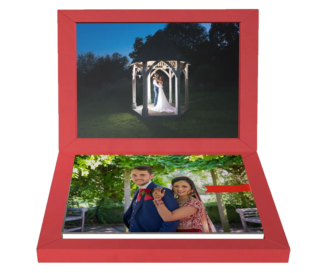 Open red photo book featuring a nighttime wedding couple under a lit gazebo on the top page and a smiling couple in traditional attire posing outdoors on the bottom page.