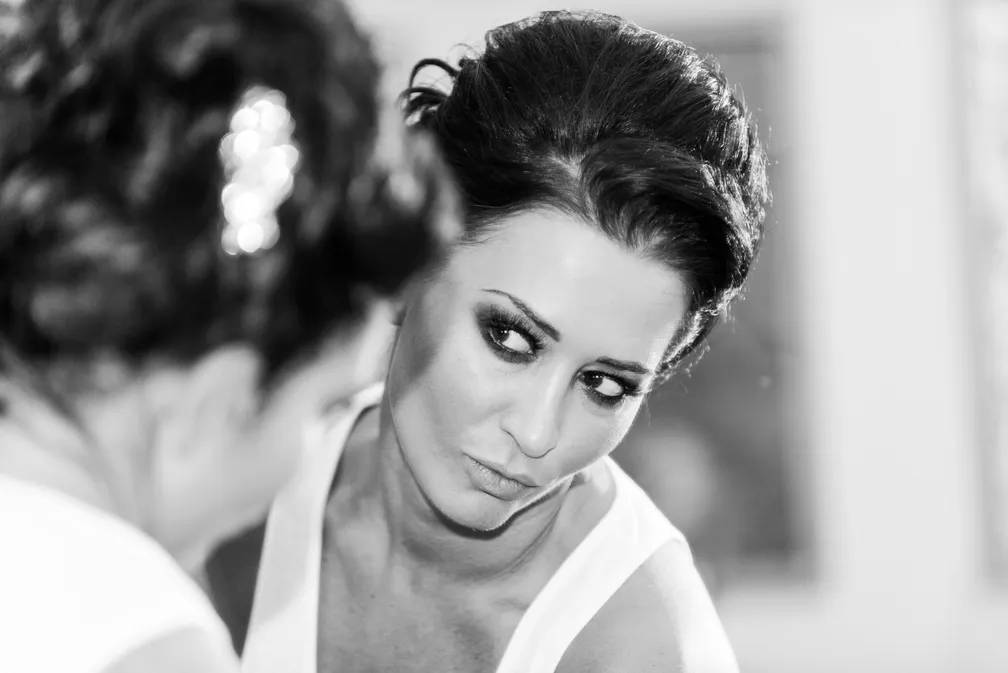 Black and white close-up of a woman looking at her reflection in a mirror.