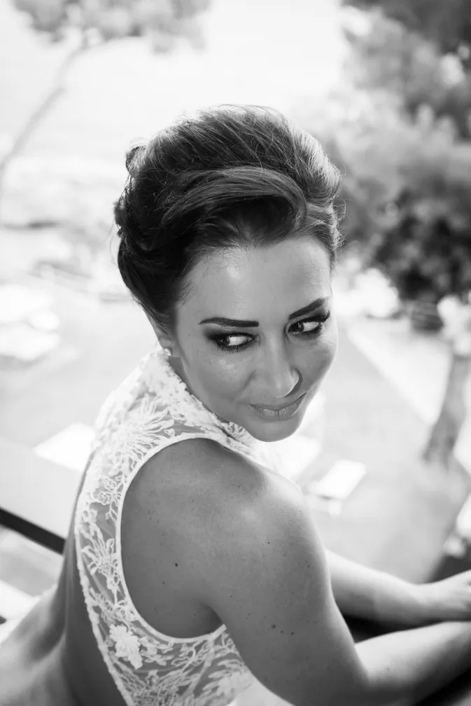 Woman in a lace dress with her hair styled, looking over her shoulder in a black and white photo.