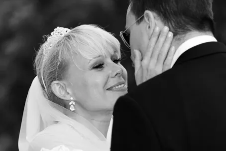 Bride smiling and gently touching groom's face in an intimate moment during wedding.
