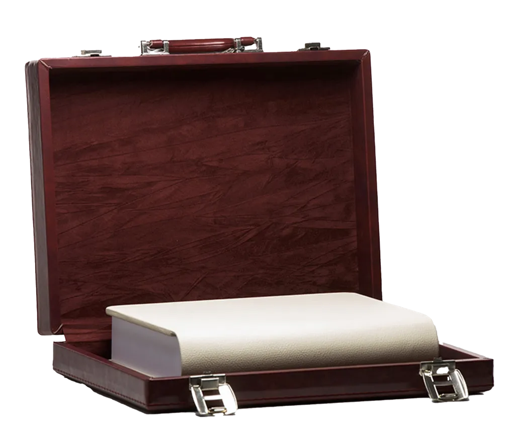 Thick white book placed inside an open brown leather briefcase.