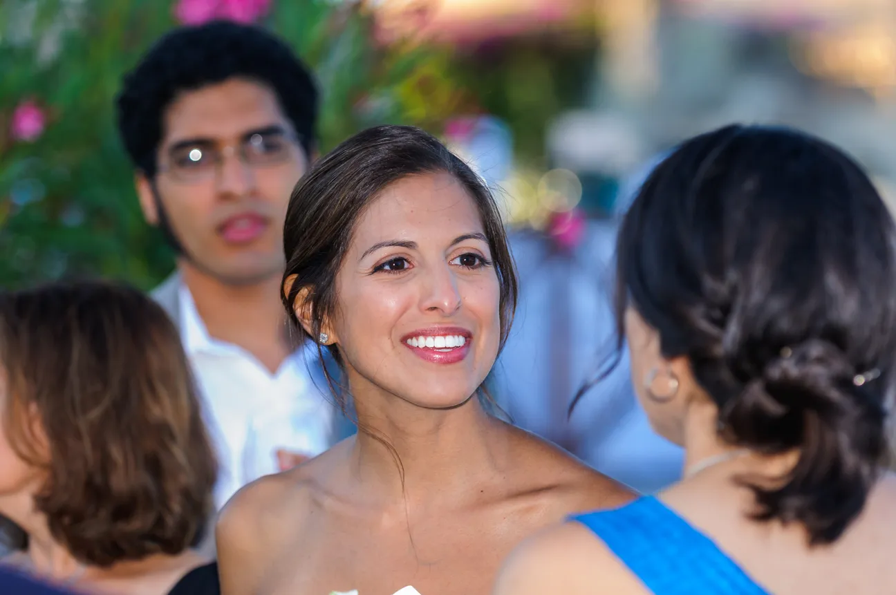 Smiling woman with dark hair talking to another woman in a blue dress at an outdoor event.