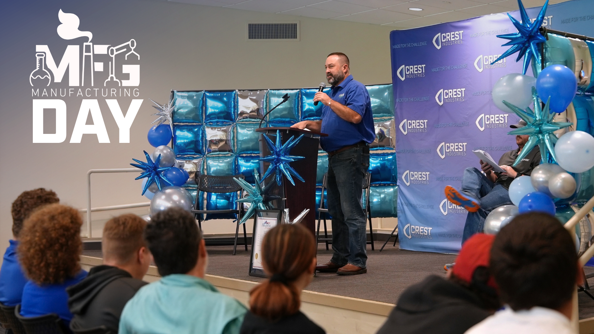 Man speaks at podium during Crest Industries Manufacturing Day 2026.