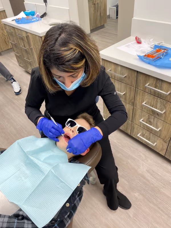 Dr. Sam cleaning a girl's teeth