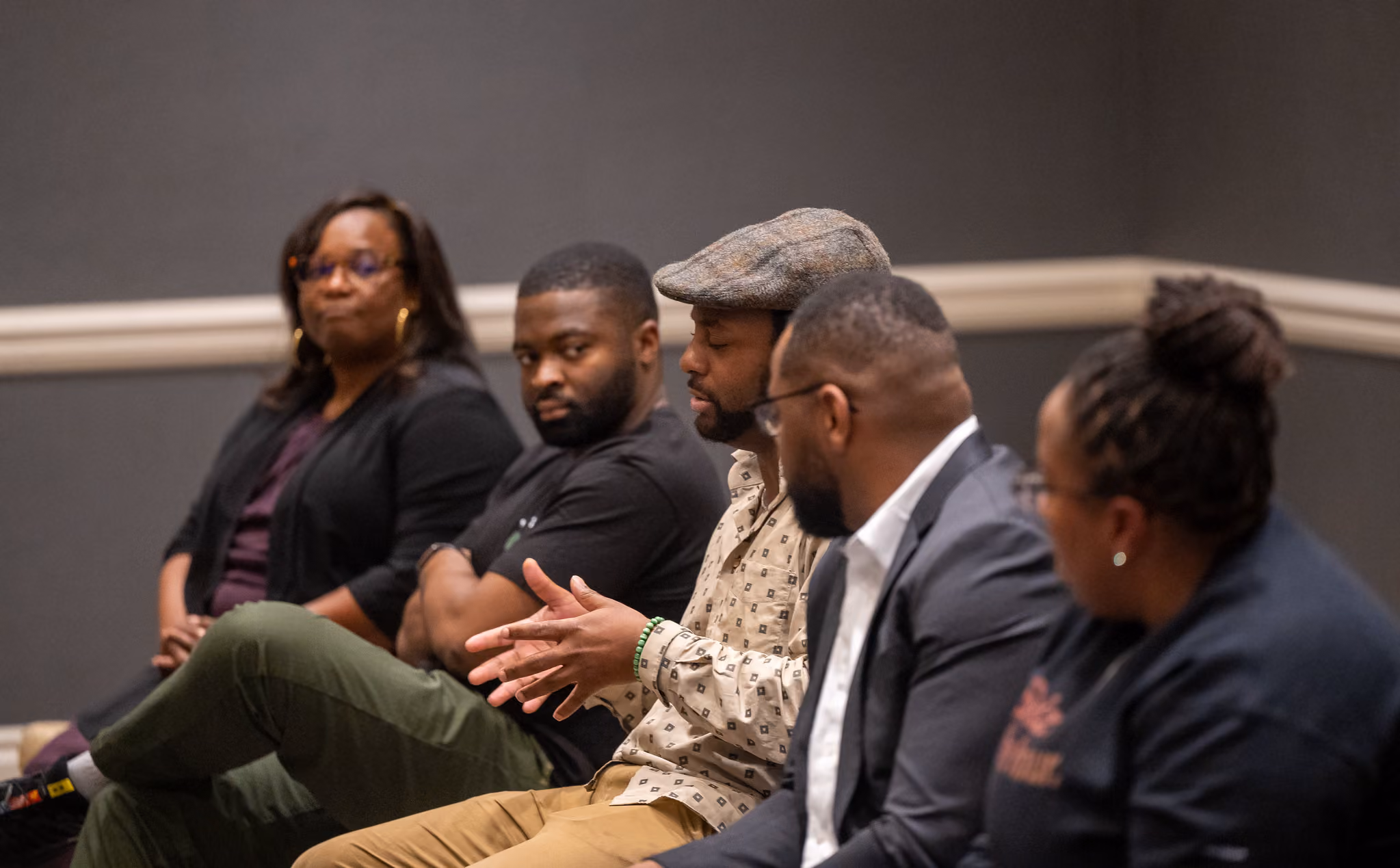 Five panelists sit in a row, one gesturing as he speaks.
