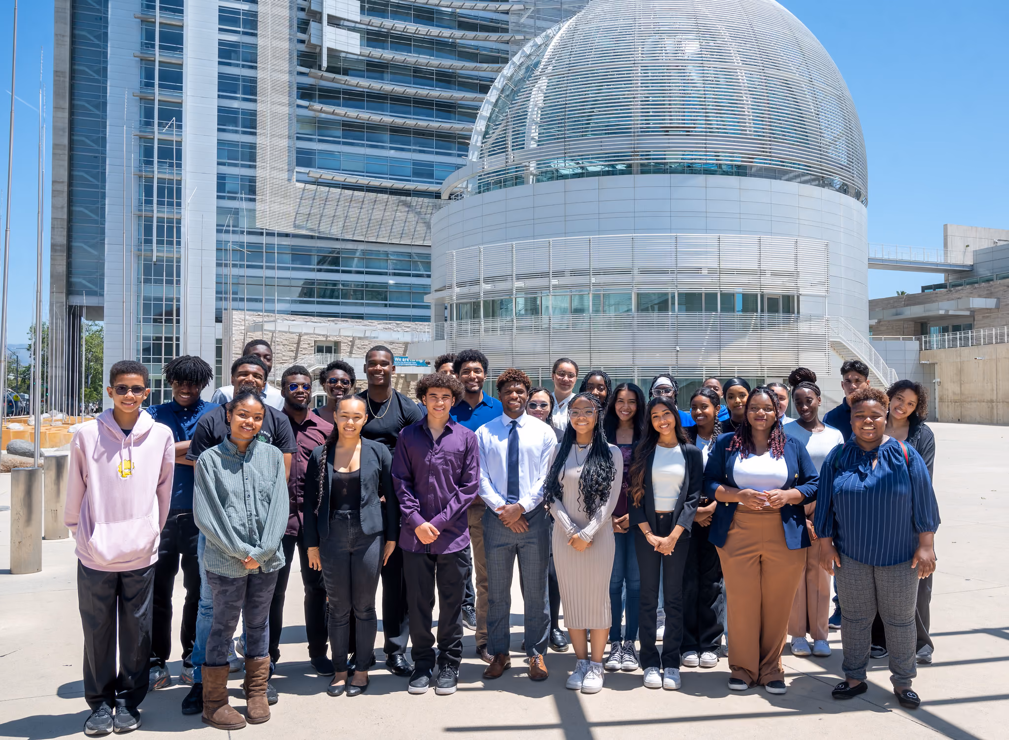 A group of participants poses for a photo in front of a glass-domed building.
