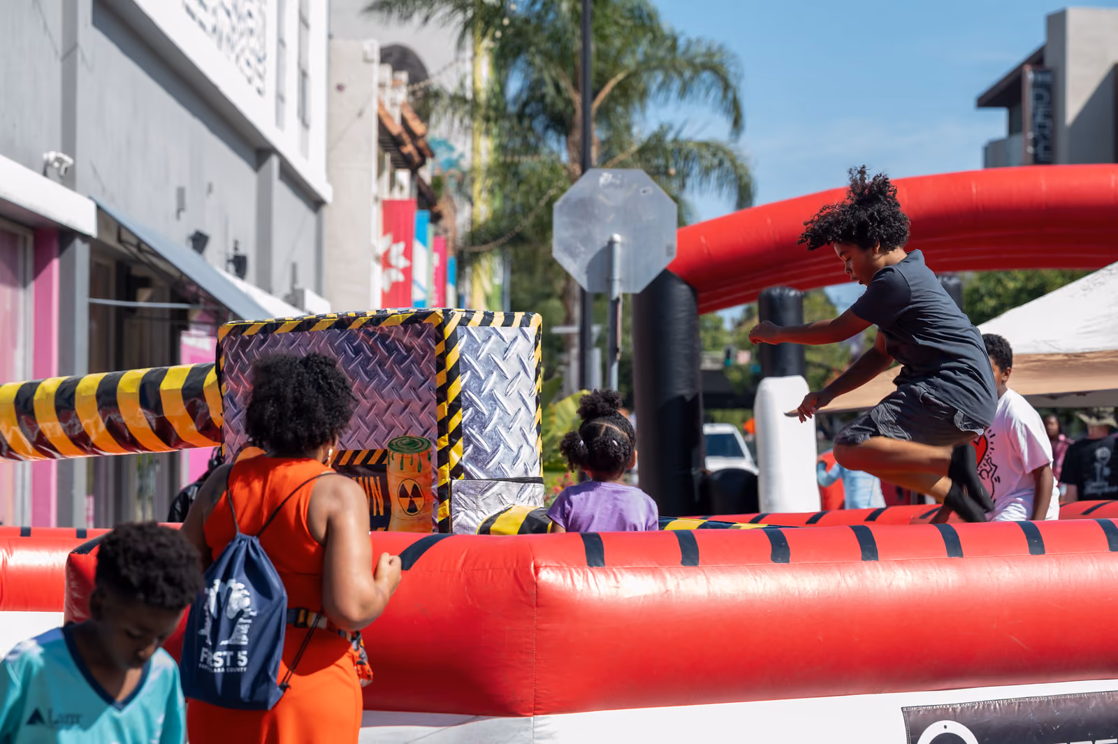 A participant jumps over a striped padded arm inside a red inflatable attraction at the festival