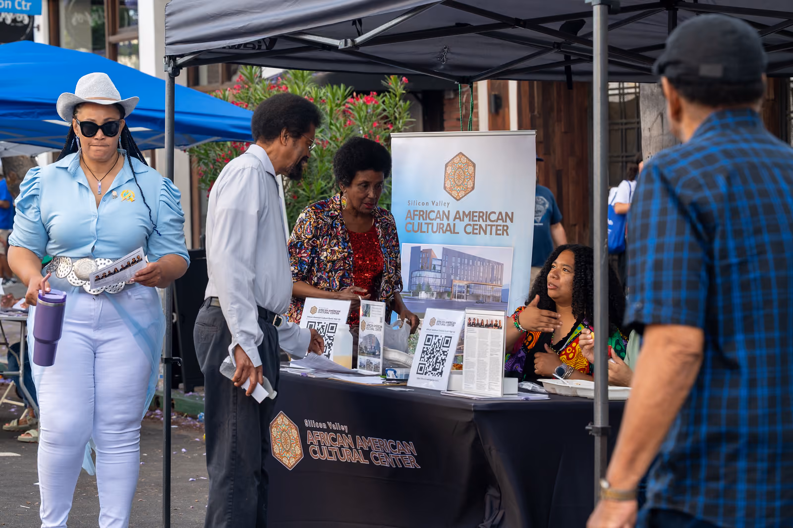 Visitors speak with staff at a Silicon Valley African American Cultural Center booth beneath a canopy