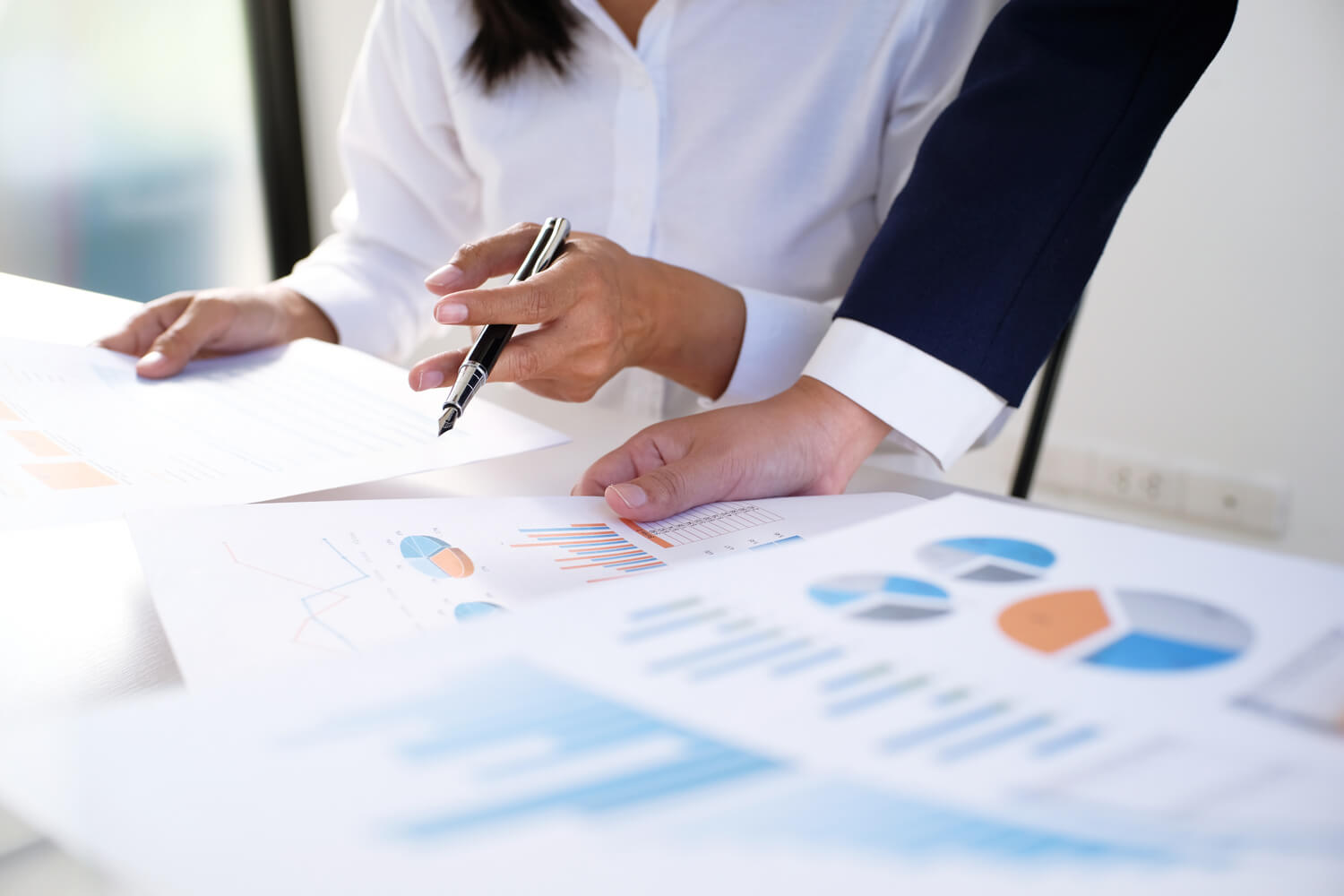 デスクの上で財務報告書やデータ分析資料を確認するビジネスパーソン