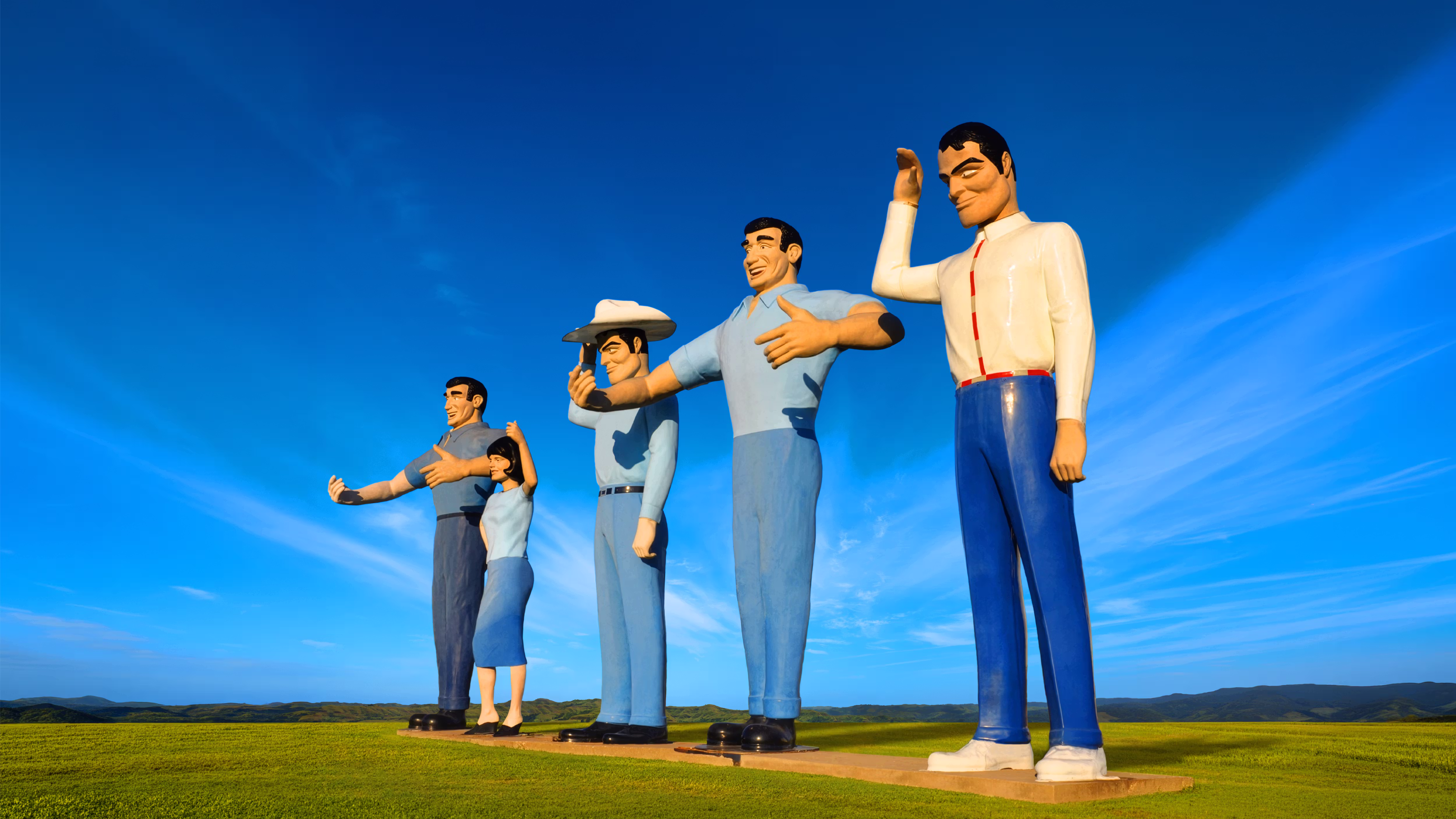 5 American fiberglass giants aka Muffler Men towering over an open grassy field