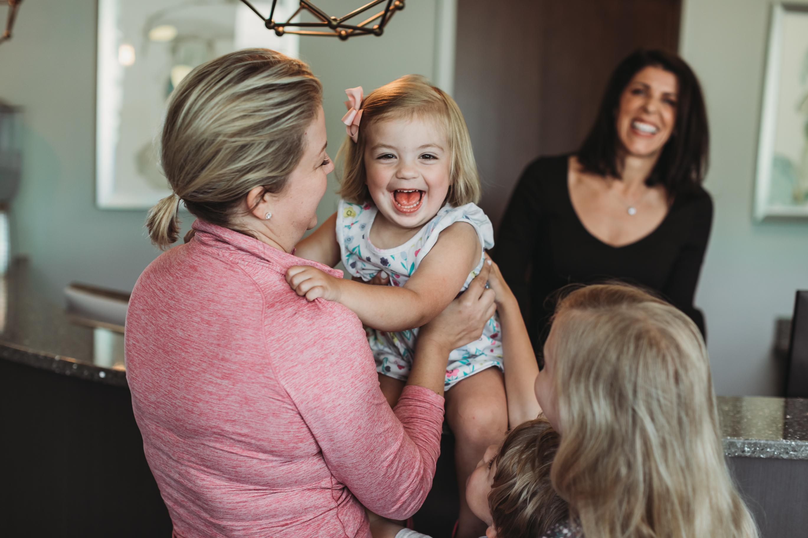 The image shows a family together in an orthodontic office waiting room to discuss early orthodontic treatment and braces options. They appear engaged in conversation, reflecting on their child's dental development and the importance of a comprehensive treatment plan for maintaining oral health.