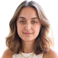 Portrait of a woman with shoulder-length light brown hair, wearing a white top and gold necklaces, against a yellow background.