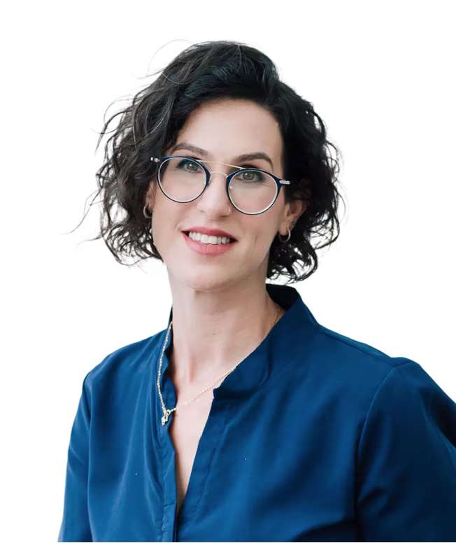 Smiling woman with short curly dark hair, wearing round glasses and a dark blue top