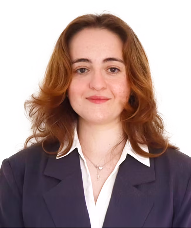 Portrait of a woman with shoulder-length auburn hair wearing a dark blazer and white collared shirt 